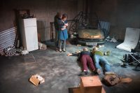 Actors on stage surrounded by debris