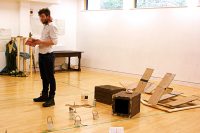 Student in rehearsal studio surrounded by boxes, jars and cardboard
