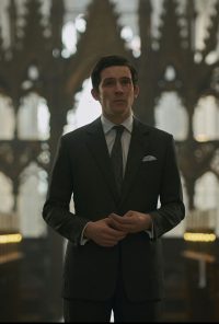 Josh O'Connor stood inside cathedral wearing a suit and tie