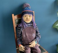 A life-size puppet of a girl with bobble hat and dungarees