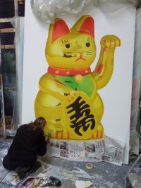 Scenic Art student completing a spray project of a chinese waving cat