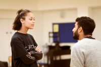 Female and male actors stood facing each other in rehearsals