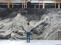 A scenic art student standing in front of a backdrop made for the Tempest