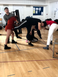 Students bent over in rehearsal
