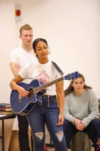 Students in rehearsal room, one stood holding a guitar