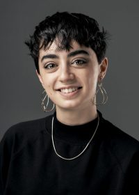headshot of woman with short black hair in a black top with hoop earrings