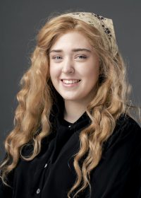 Headshot of woman with blonde curly hair and a headband