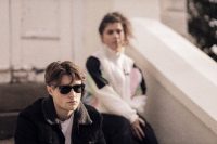 Show image for North of Providence: man with sunglasses and woman sitting in the background, 80s style