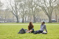 Two students sitting on the grass in Queen's Square