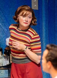 Actress with short brown hair in a stripy top and red trousers